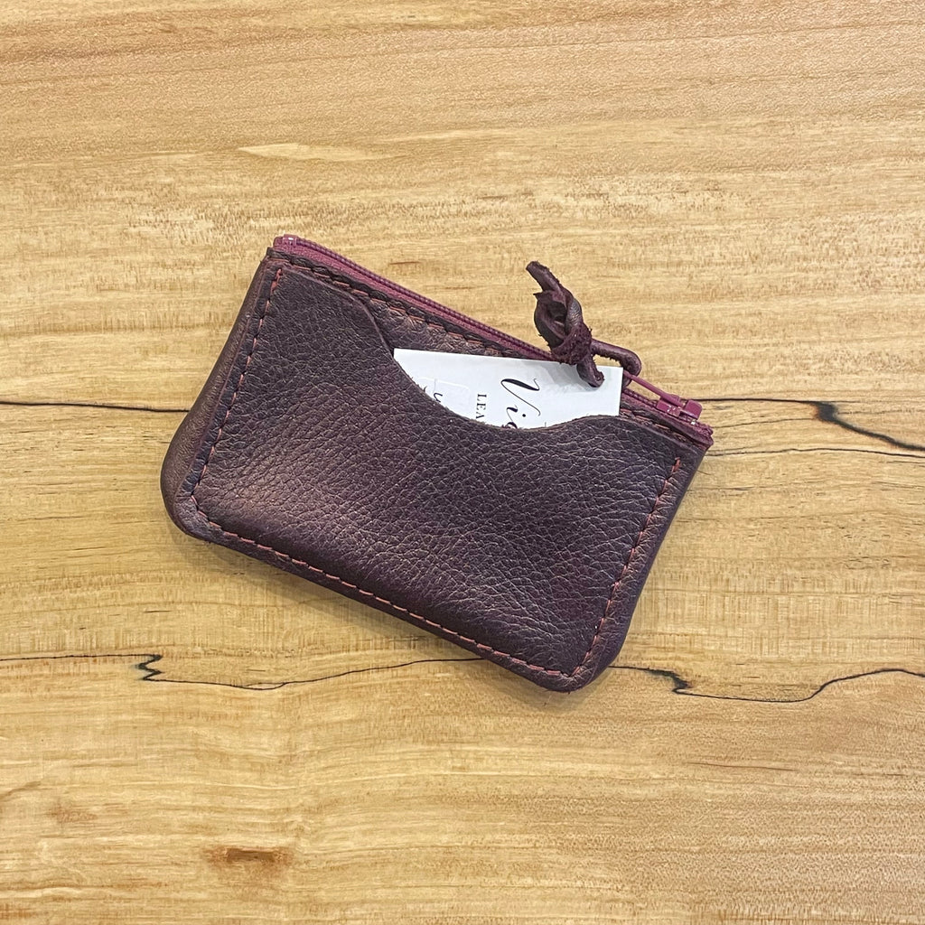 Maroon leather cardholder on a wooden surface