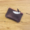 Maroon leather cardholder on a wooden surface