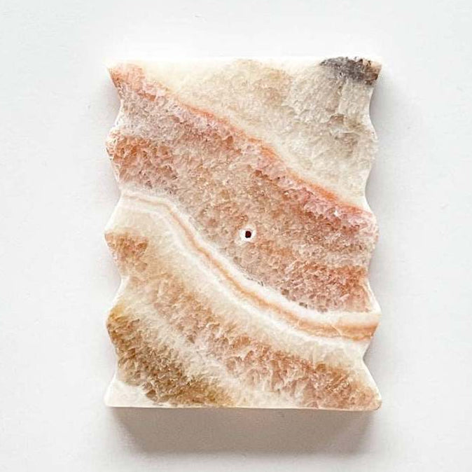 white and orange stone cut flat with zigzag sides, hole in the center