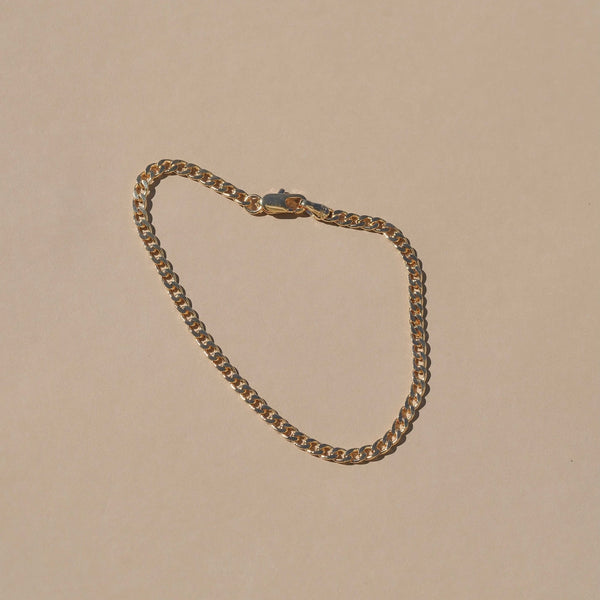 Gold chain necklace on a beige background