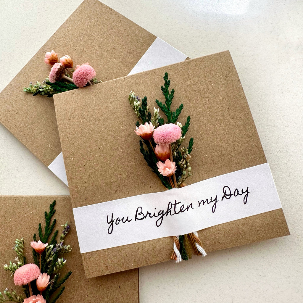 Kraft paper card with floral embellishments and 'You Brighten My Day' text on a light background