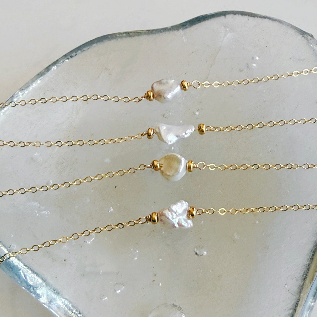 Gold necklaces with pearl beads on a white stone surface