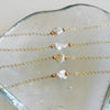 Gold necklaces with pearl beads on a white stone surface