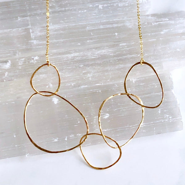 Gold necklace with interlocking rings on a textured white background