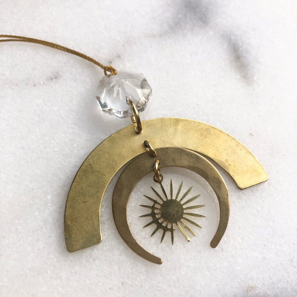 Brass pendant with sun design on a white marble surface