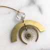 Brass pendant with sun design on a white marble surface