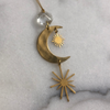 Gold pendant with moon and sun design on a textured gray background