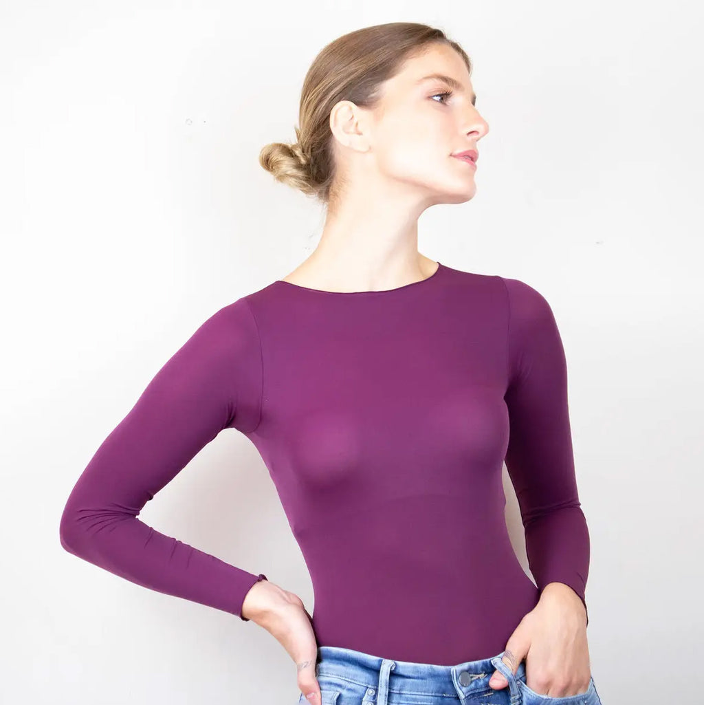 Woman wearing a purple long-sleeve top against a white background