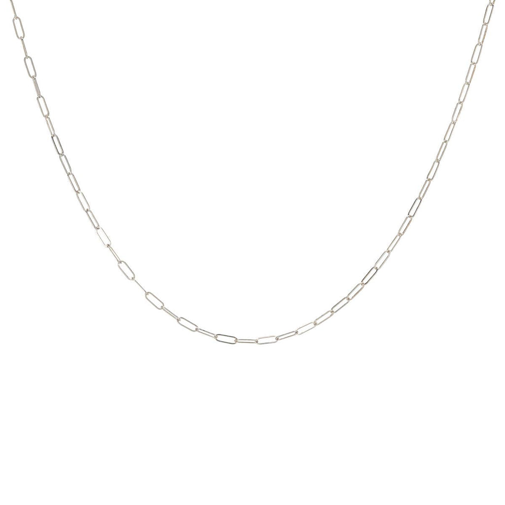 A delicate sterling silver layering necklace chain laid out on a plain background.