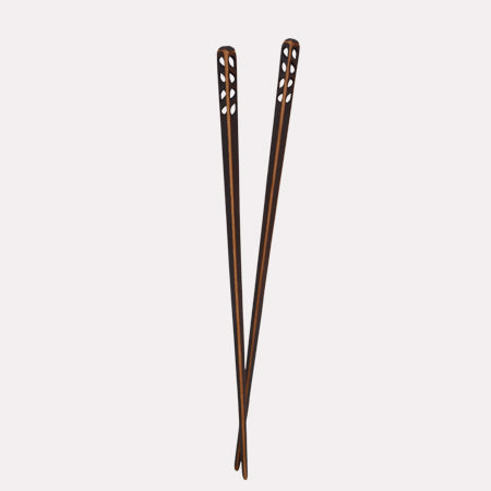 A pair of blackened wooden chopsticks with a flame pattern, standing upright against a white background.